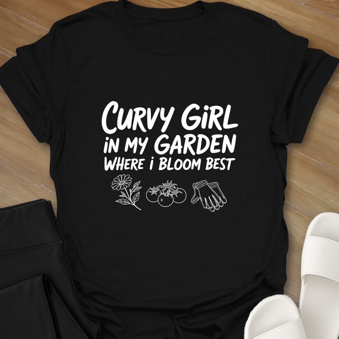 Black Curvy girl gardening shirt with white hand-lettered text reading “Curvy Girl in My Garden Where I Bloom Best” and garden icons on black background