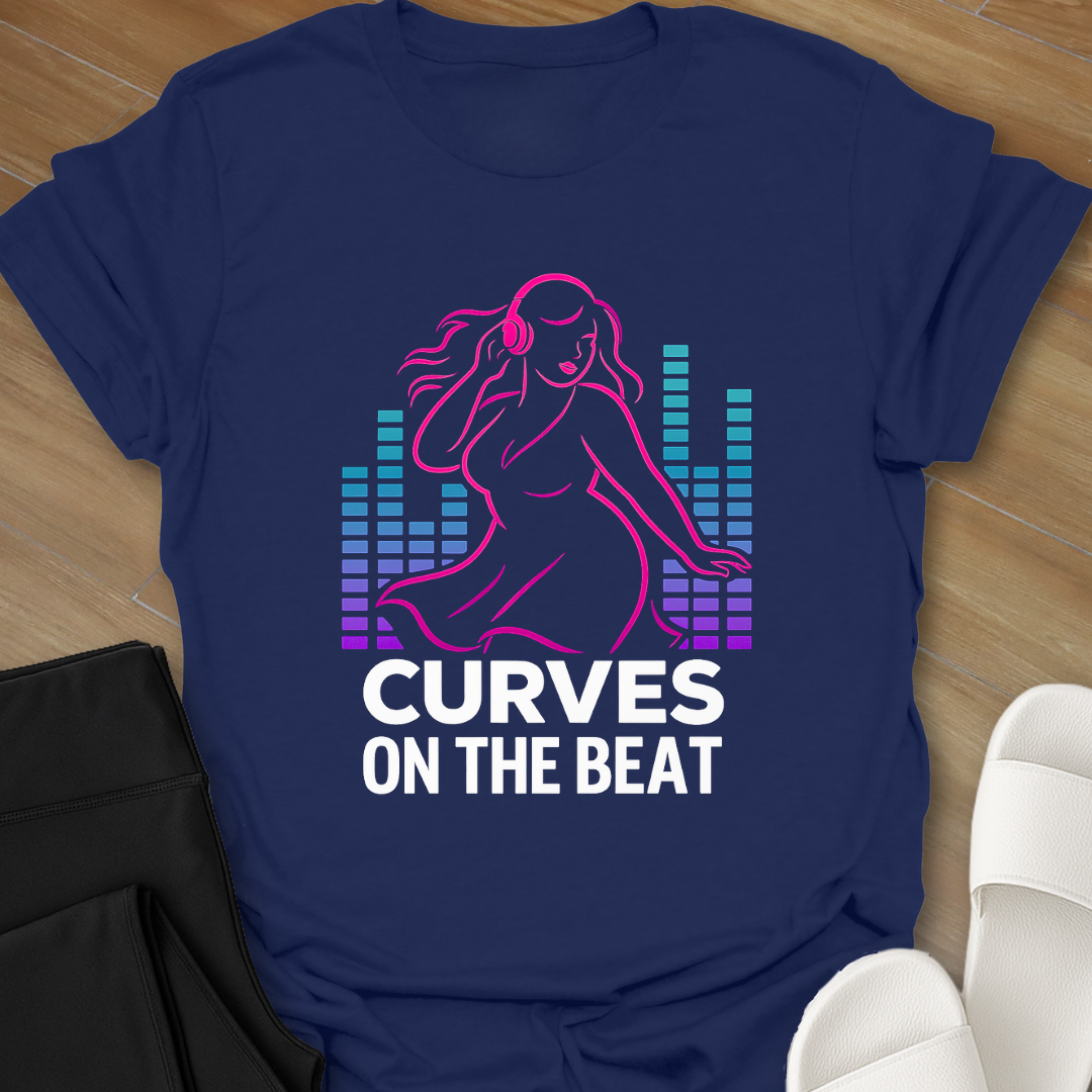 Blue t-shirt with a graphic of a woman and text 'Curves on the Beat' on a wooden surface.