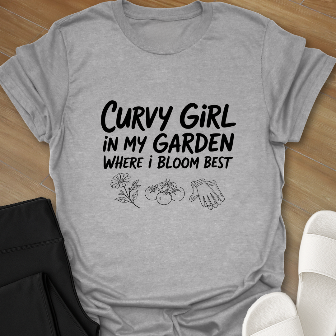 Gray Curvy girl gardening shirt with white hand-lettered text reading “Curvy Girl in My Garden Where I Bloom Best” and garden icons on black background